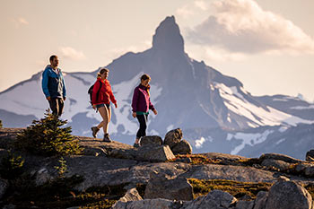 one guy and 2 girls hiking in the alpine with Whistler Peak in the background